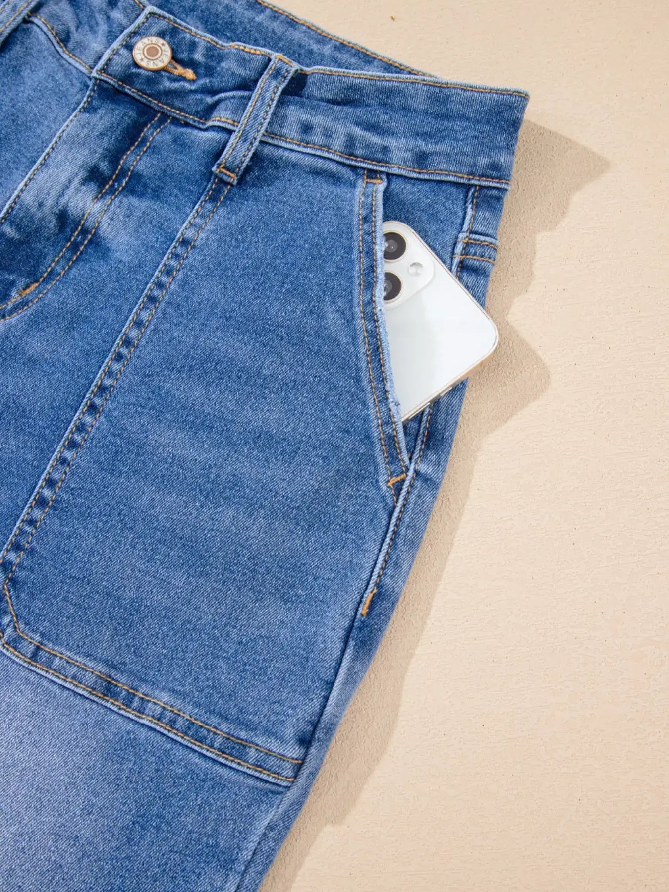 High-Waisted Wide Leg Flare Jeans with smartphone in pocket against a light background.
