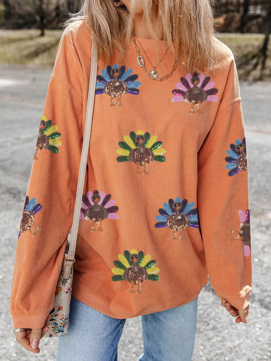 Turkey Graphic Corded Baggy Sweatshirt featuring a colorful turkey graphic on a cozy orange background.