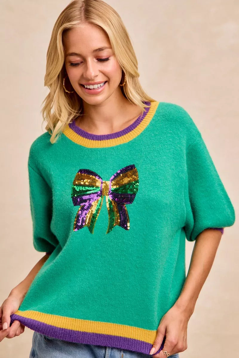 BiBi Mardi Gras Sequin Ribbon Patched Sweater featuring vibrant sequin bow design and colorful trim.