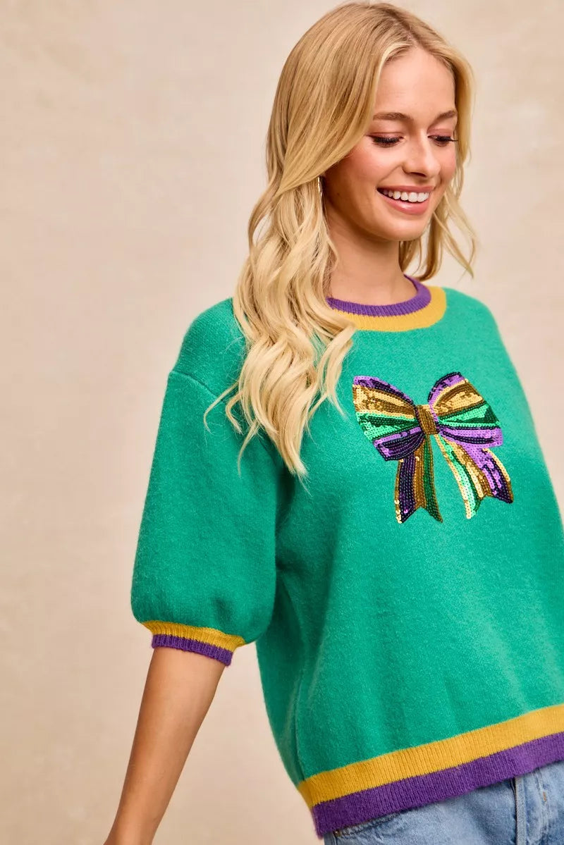 BiBi Mardi Gras Sequin Ribbon Patched Sweater featuring vibrant sequin bow detail and colorful design.