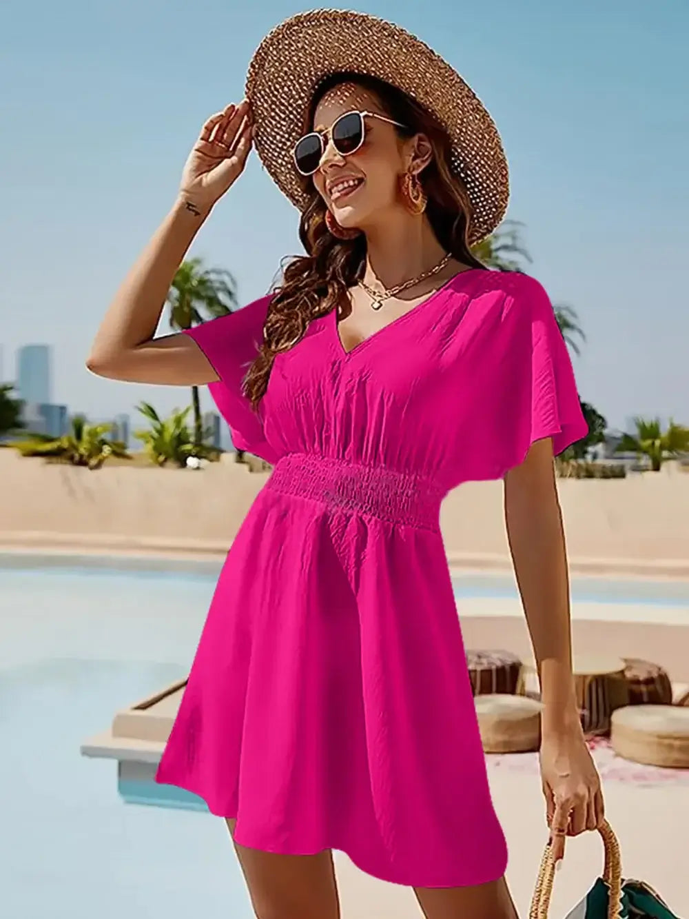 Smocked V-neck short sleeve dress in bright pink, paired with a hat and sunglasses, perfect for summer outings.