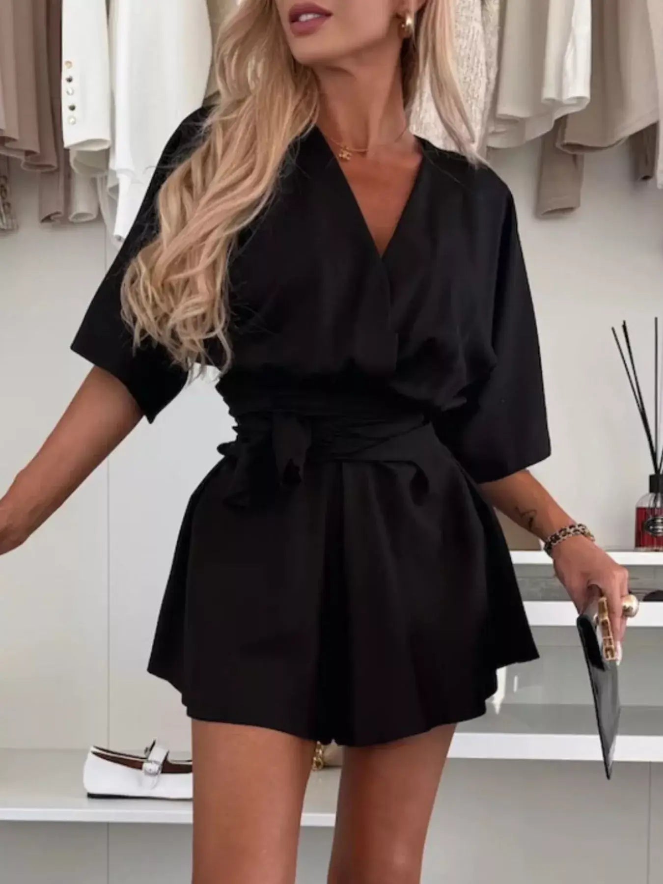 Woman wearing Full Size Surplice Tie Waist Romper in black, featuring surplice neckline and tie waist for a chic look.