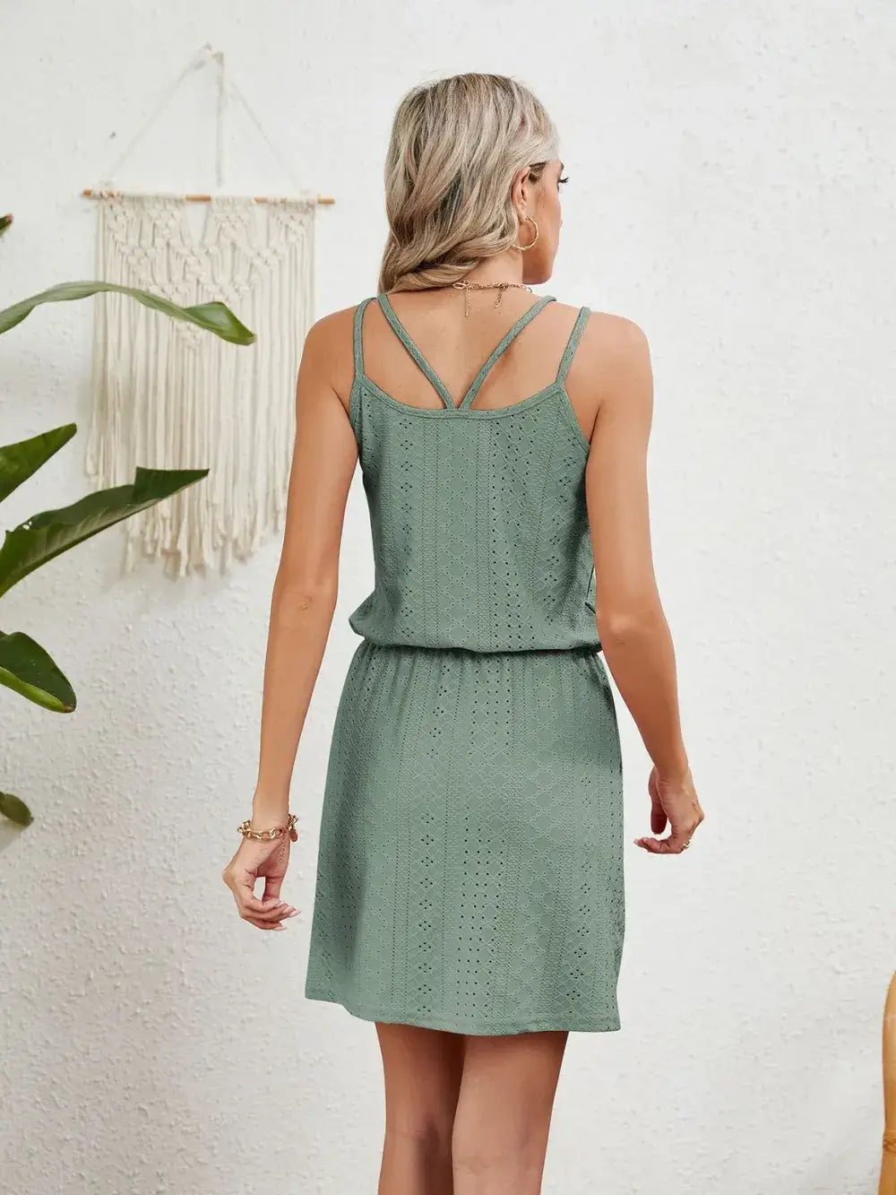 Back view of a woman in a green eyelet scoop neck sleeveless dress, showcasing its delicate detailing and casual style.