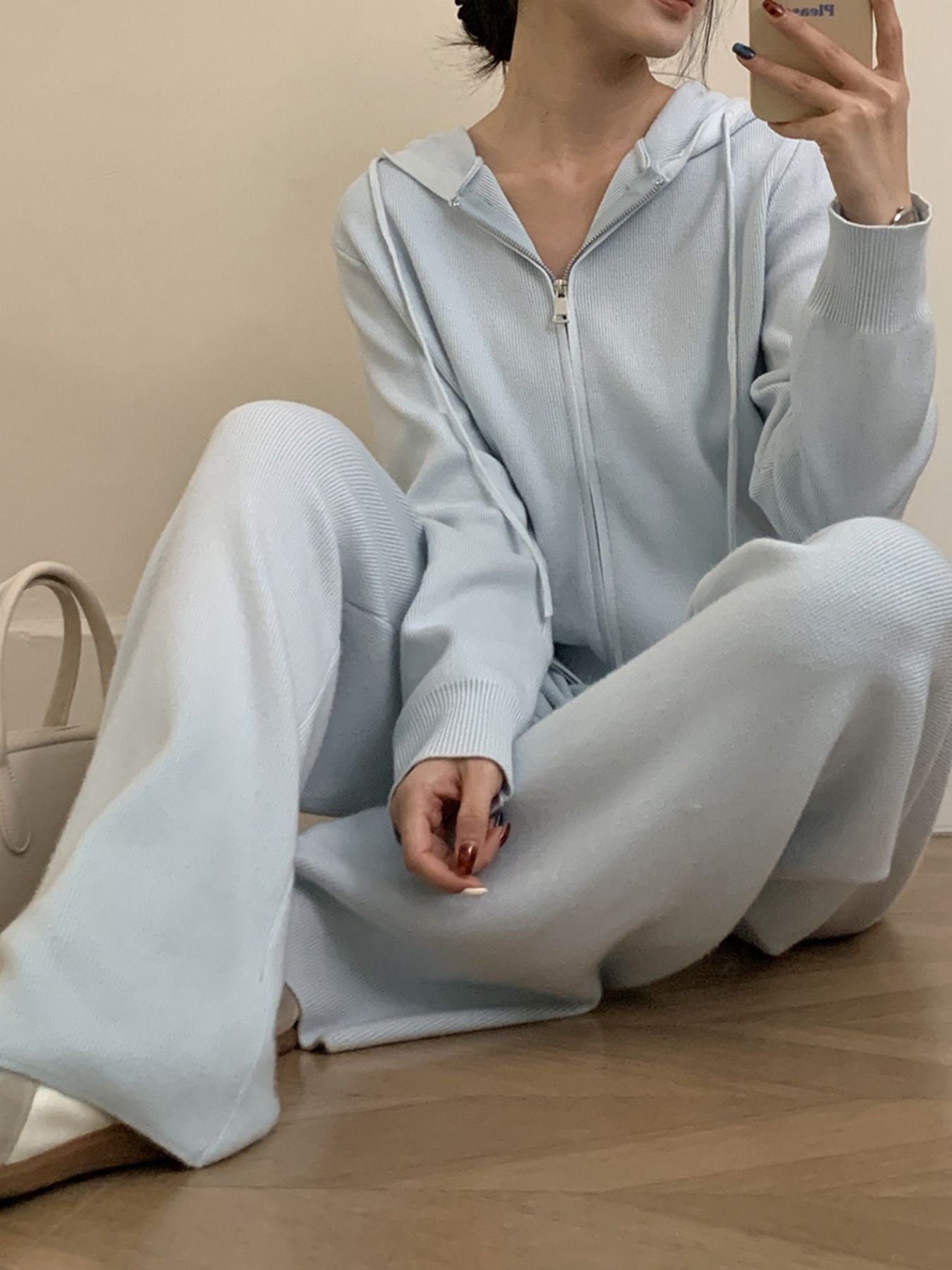 Woman sitting in light blue Zip Up Cardigan and Wide Leg Pants Knit Set, showcasing a cozy two-piece outfit.