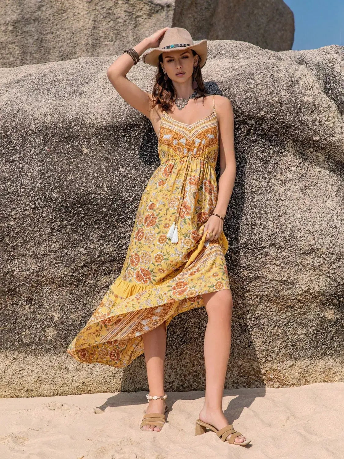 Model wearing a Tassel Printed Tiered Cami Dress against a rocky beach backdrop, showcasing a bohemian summer vibe.