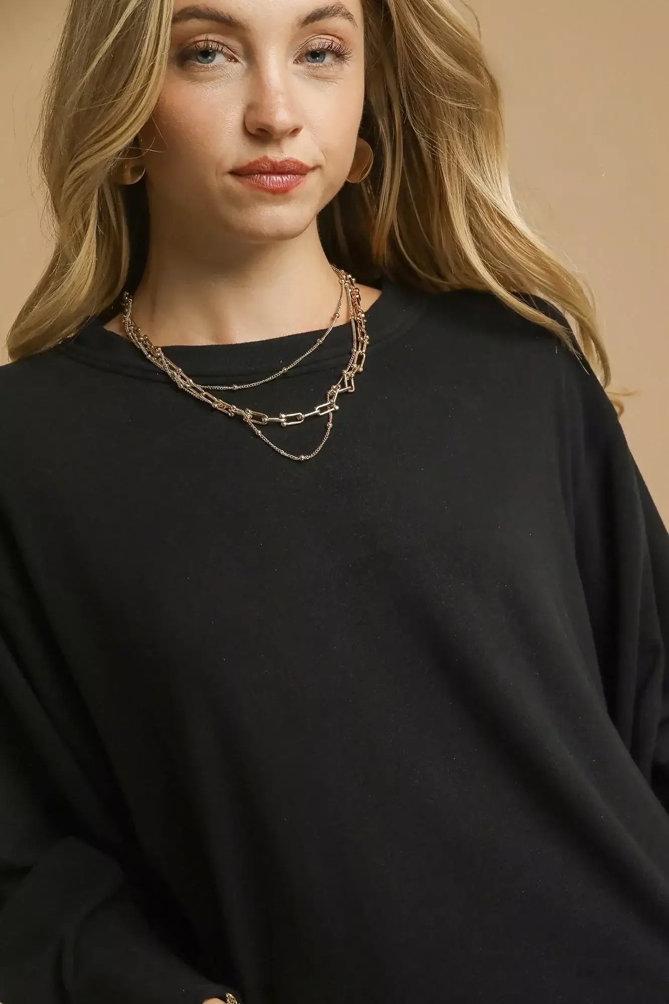 Model wearing an oversized black Umgee brushed fleece crewneck top with layered necklaces, against a neutral background.