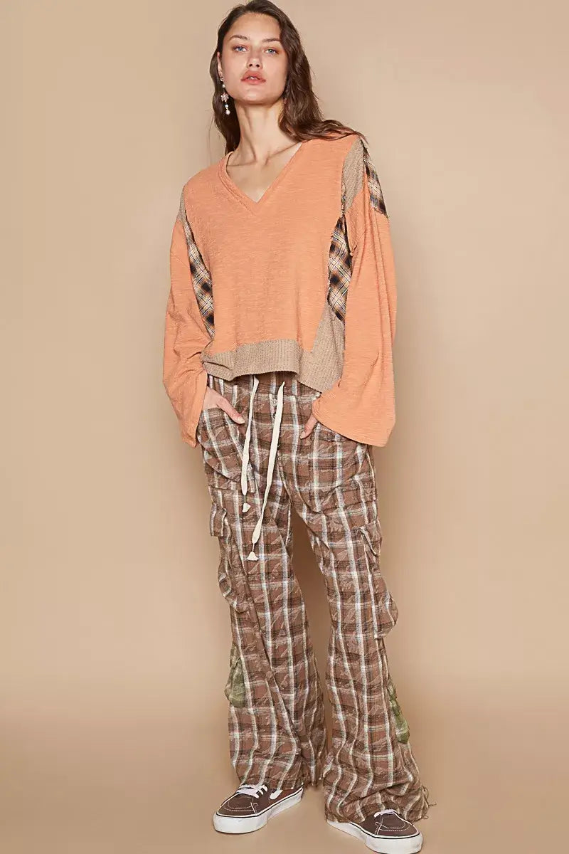 Model wearing POL V-Neck Long Sleeve Plaid Contrast Top with Texture Knit and plaid pants against a beige background.