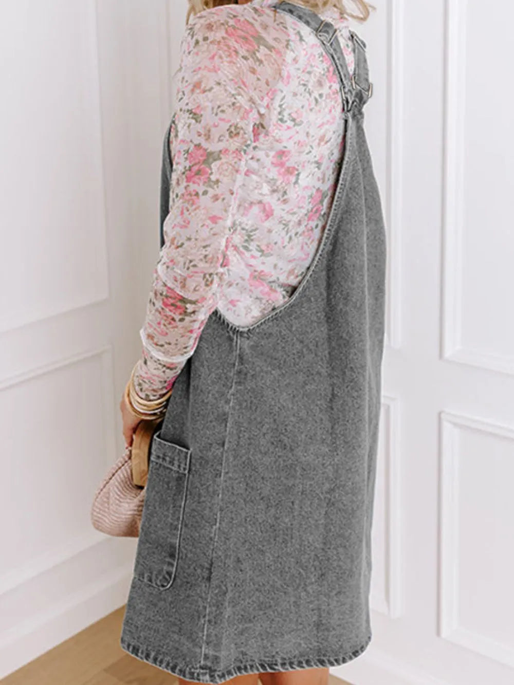 Wide Strap Button Down Denim Overall Dress styled with a floral top, showcasing a casual look from the back.