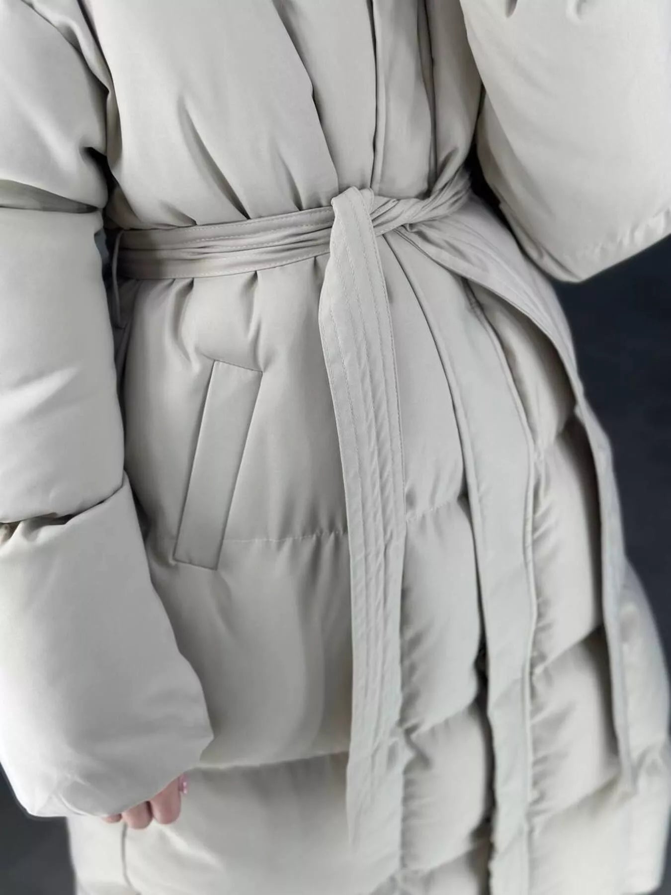 Longline Padded Winter Coat Belted in beige, showcasing the belted waist and pocket detail for added warmth and style.