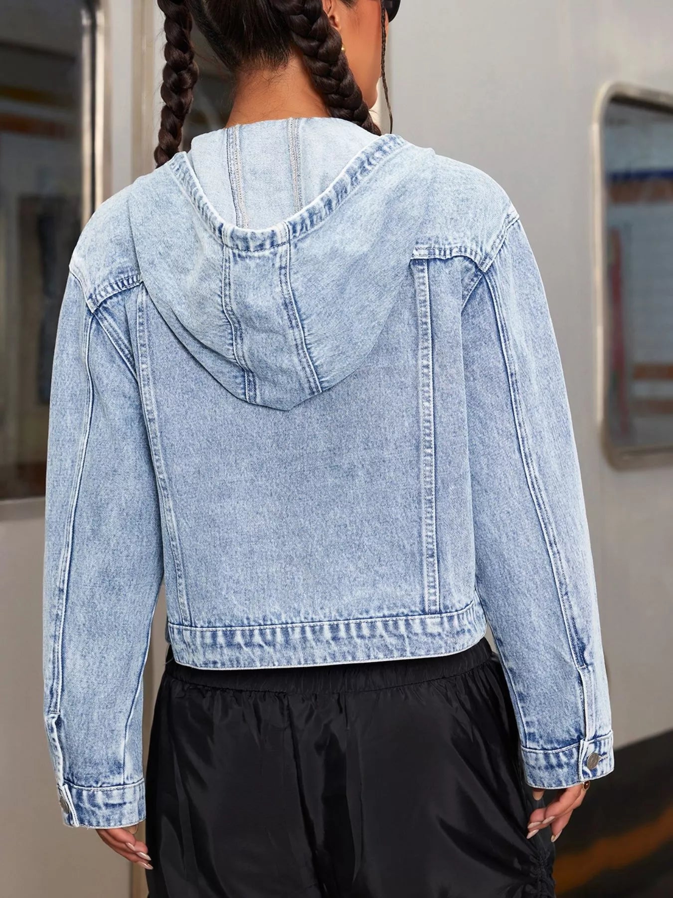 Back view of a woman wearing a Hooded Drawstring Cropped Denim Jacket for Women with hood and cropped fit.