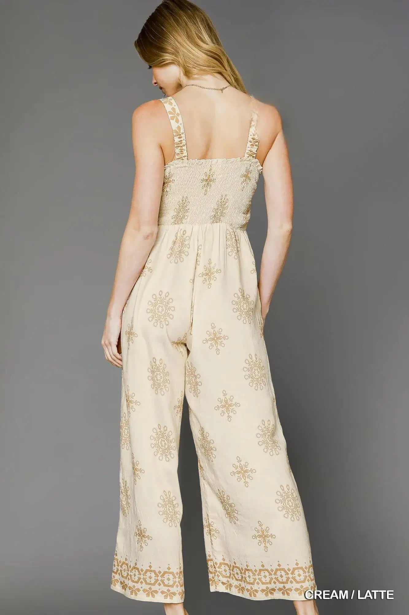 Back view of the Umgee Smocked Printed Wide Leg Jumpsuit in cream and latte with floral design.