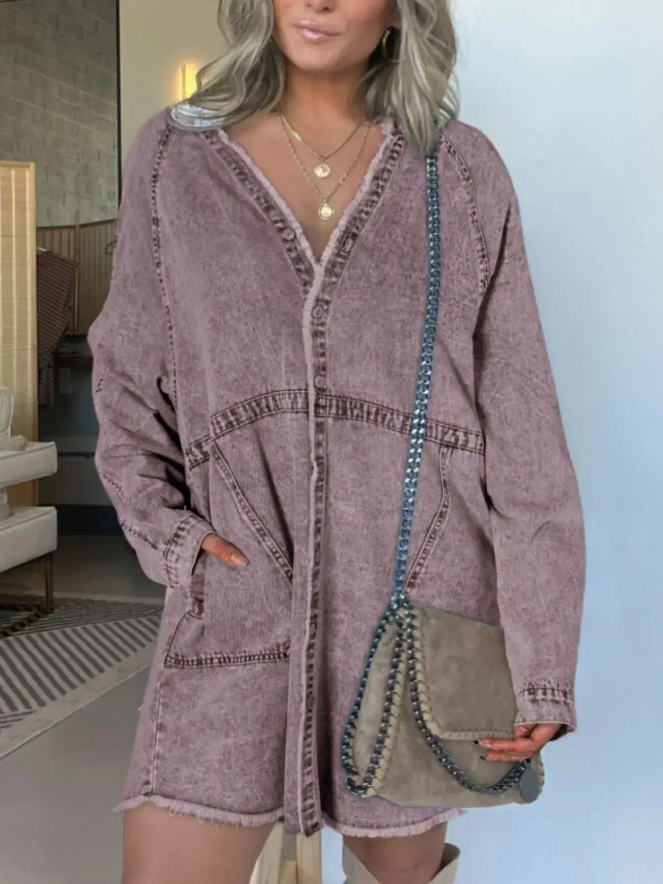 Plus size woman in oversized mauve denim dress with pockets, styled with a crossbody bag, showcasing comfort and style.