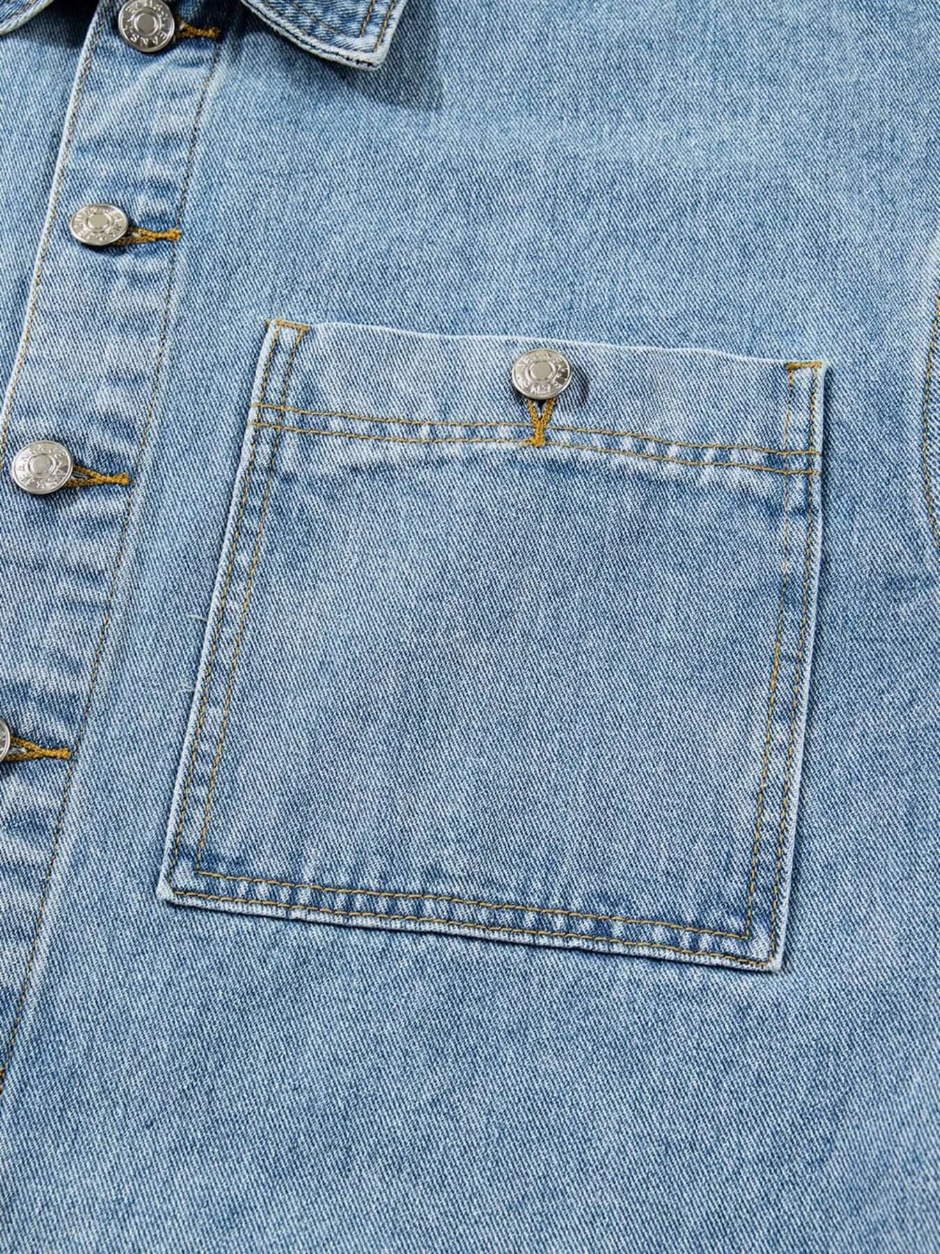 Close-up of a patched pocket on a light blue denim jacket, highlighting its unique design and button detail.