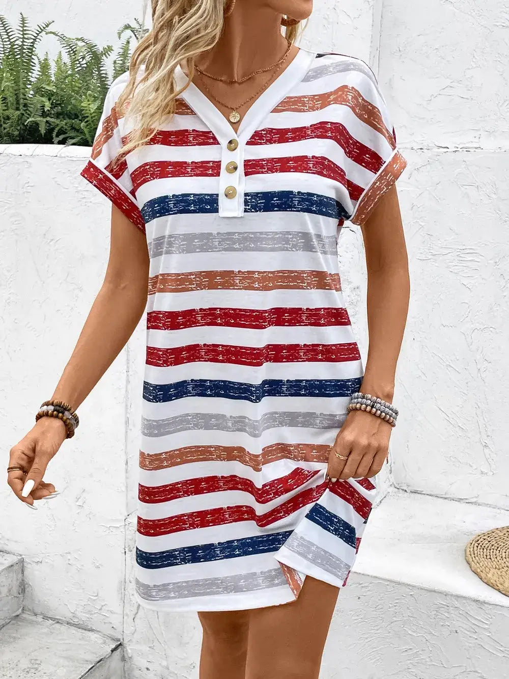 Woman wearing a striped v-neck short sleeve dress with buttons, perfect for casual outings and stylish occasions.