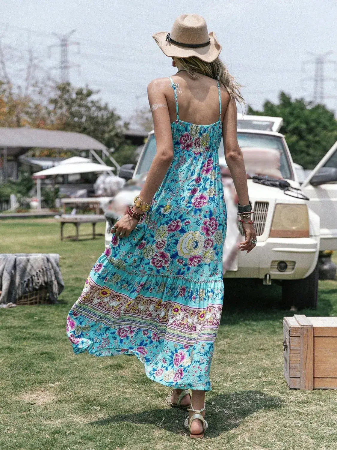 Model wearing a Tassel Floral Print Tiered Cami Dress with adjustable straps and hat, set against a summer outdoor backdrop.