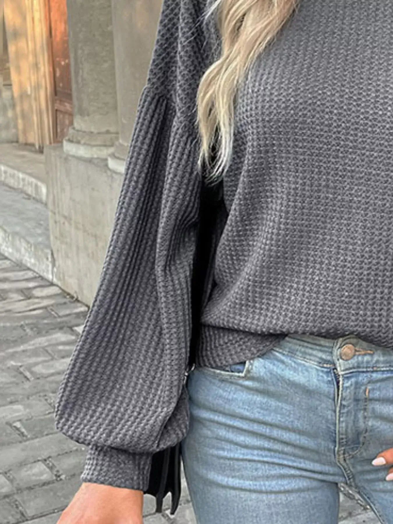 Waffle knit round neck top with long sleeves, styled with light blue jeans, featuring a cozy textured fabric.