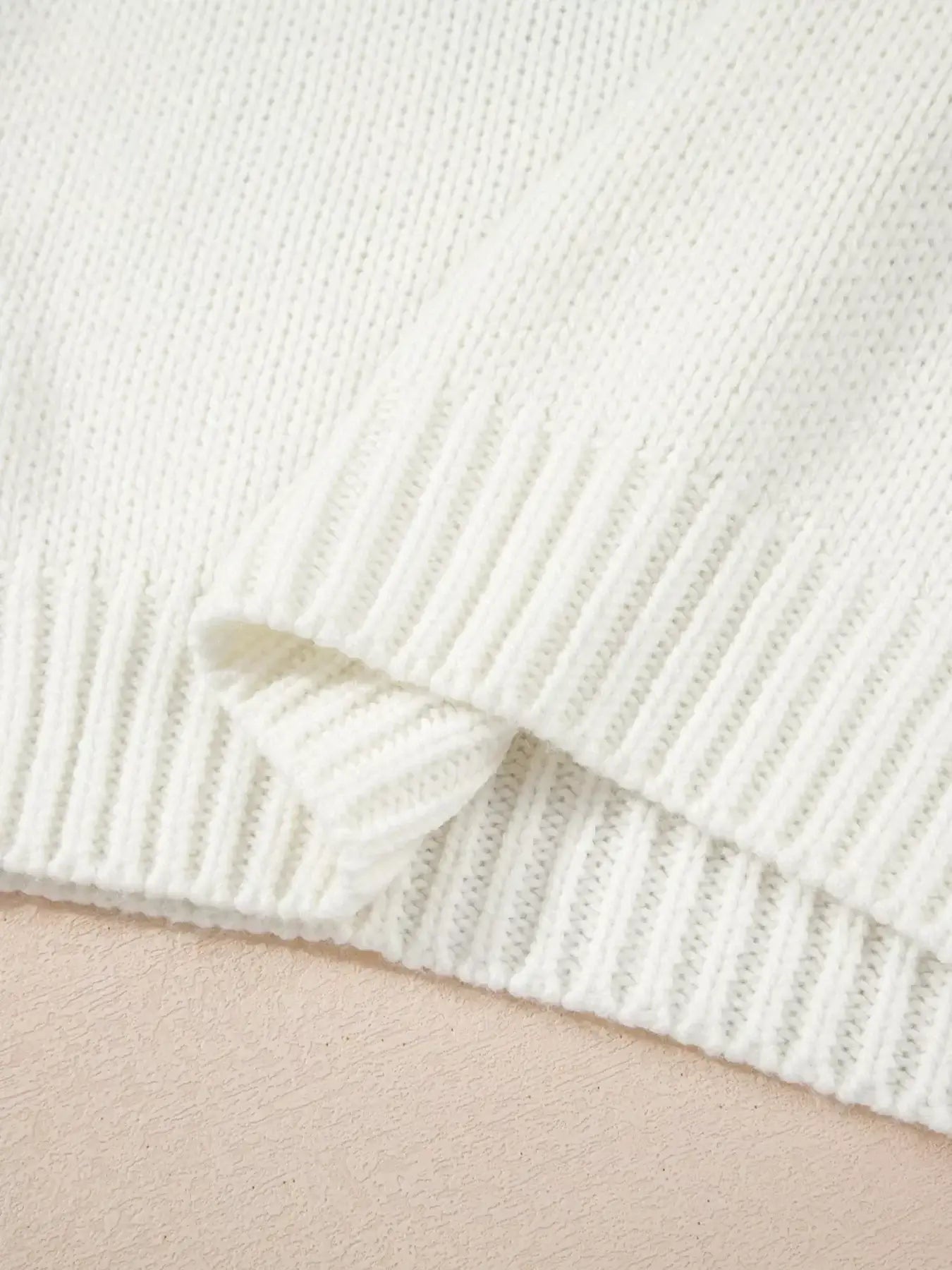Close-up of the cozy knit fabric and ribbed hem of the embroidered bow boots graphic drop shoulder sweater.
