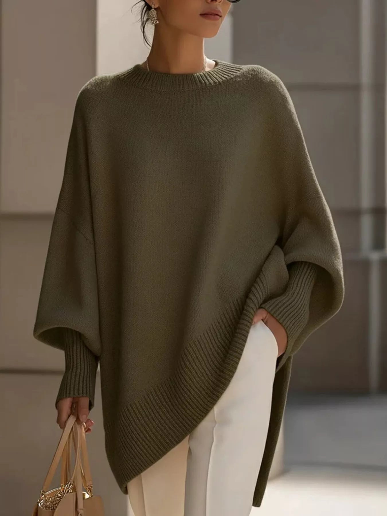 Stylish woman wearing an Oversized Batwing Sleeve Knit Sweater in olive green, paired with white pants.