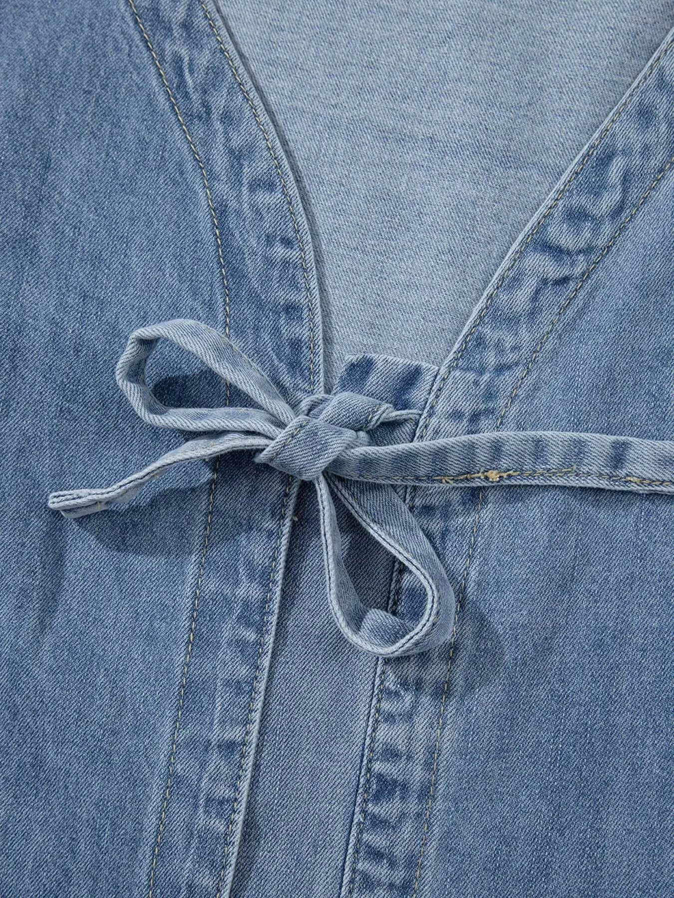 Close-up of the tied front detailing on a denim blouse with a soft blue fabric and chic design.
