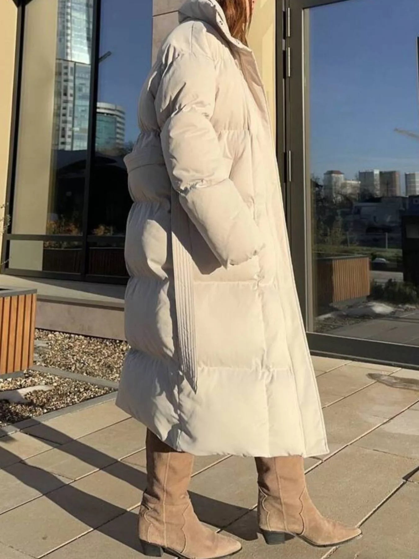 Longline Padded Winter Coat Belted warm women jacket displayed outdoors near a building with city view.