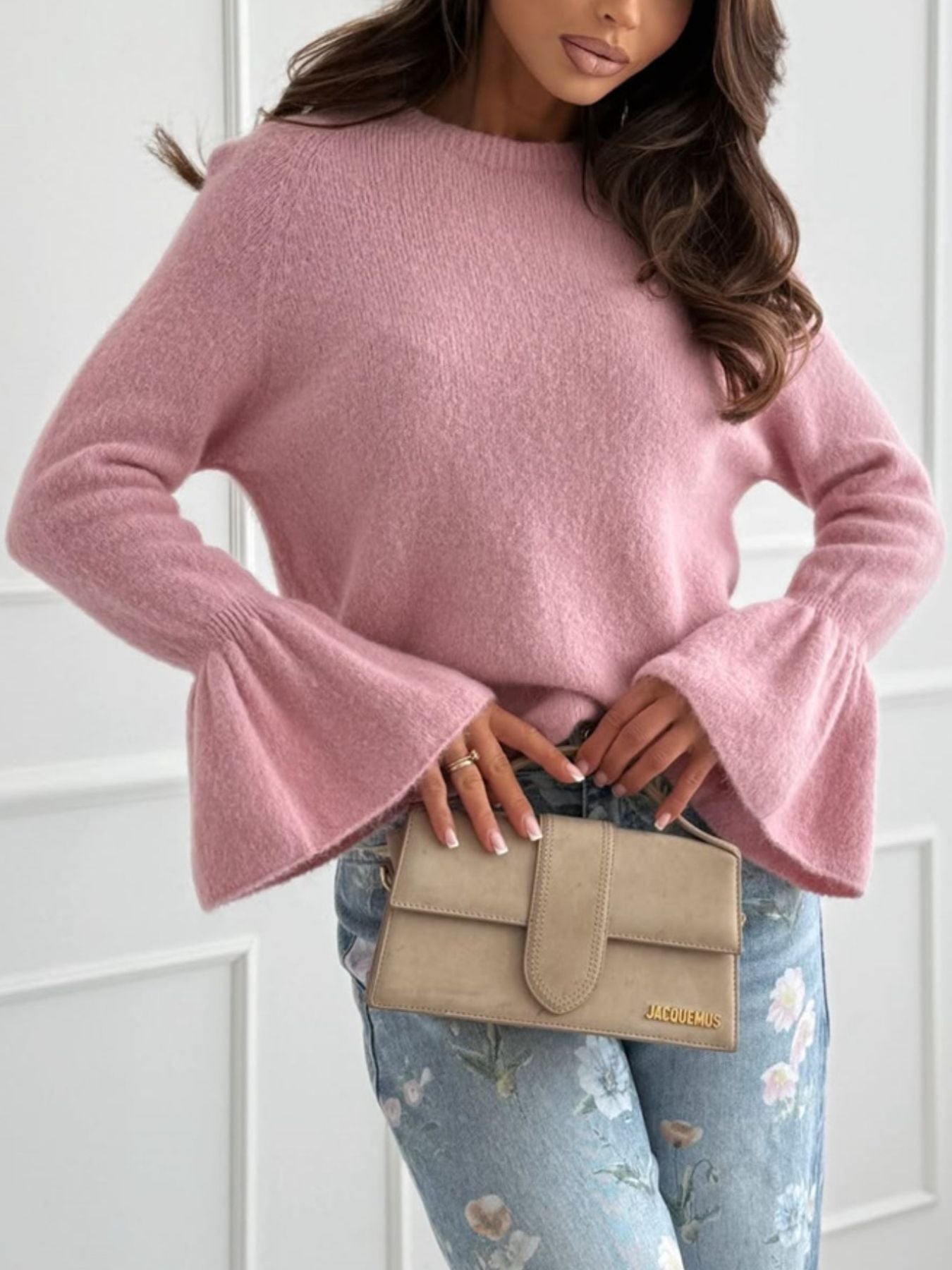 Round Neck Flounce Sleeve Sweater in soft pink featuring flared sleeves styled with a beige clutch and floral jeans.