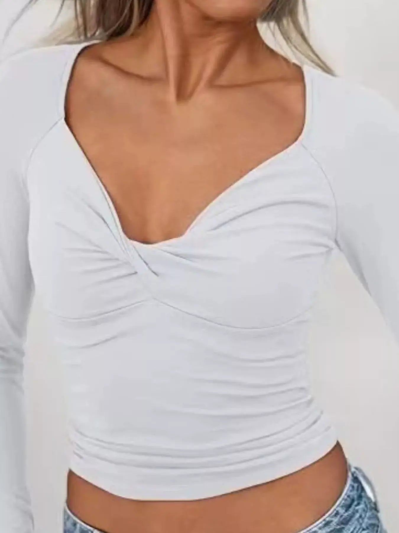 Model wearing a white twist front long sleeve fitted t-shirt showcasing its stylish design and fitted silhouette.