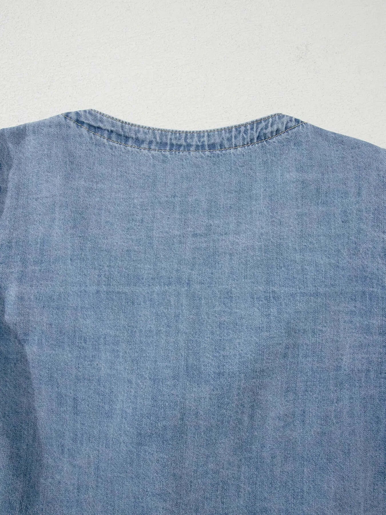 Back view of a light blue denim top featuring a simple round neckline and soft fabric.