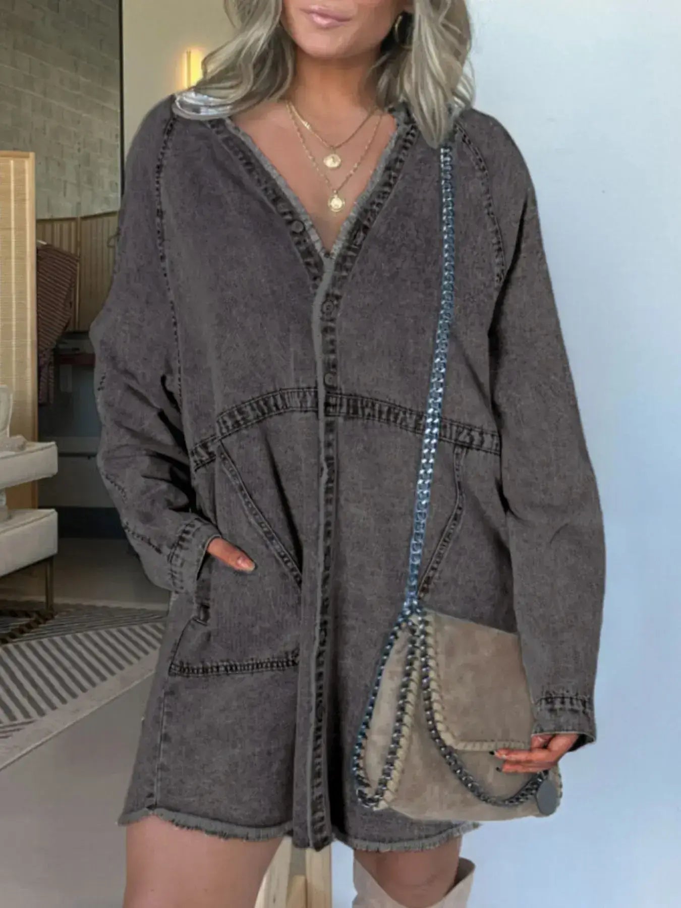 Woman wearing a button-front denim shirt dress with pockets and a handbag, styled casually in an indoor setting.