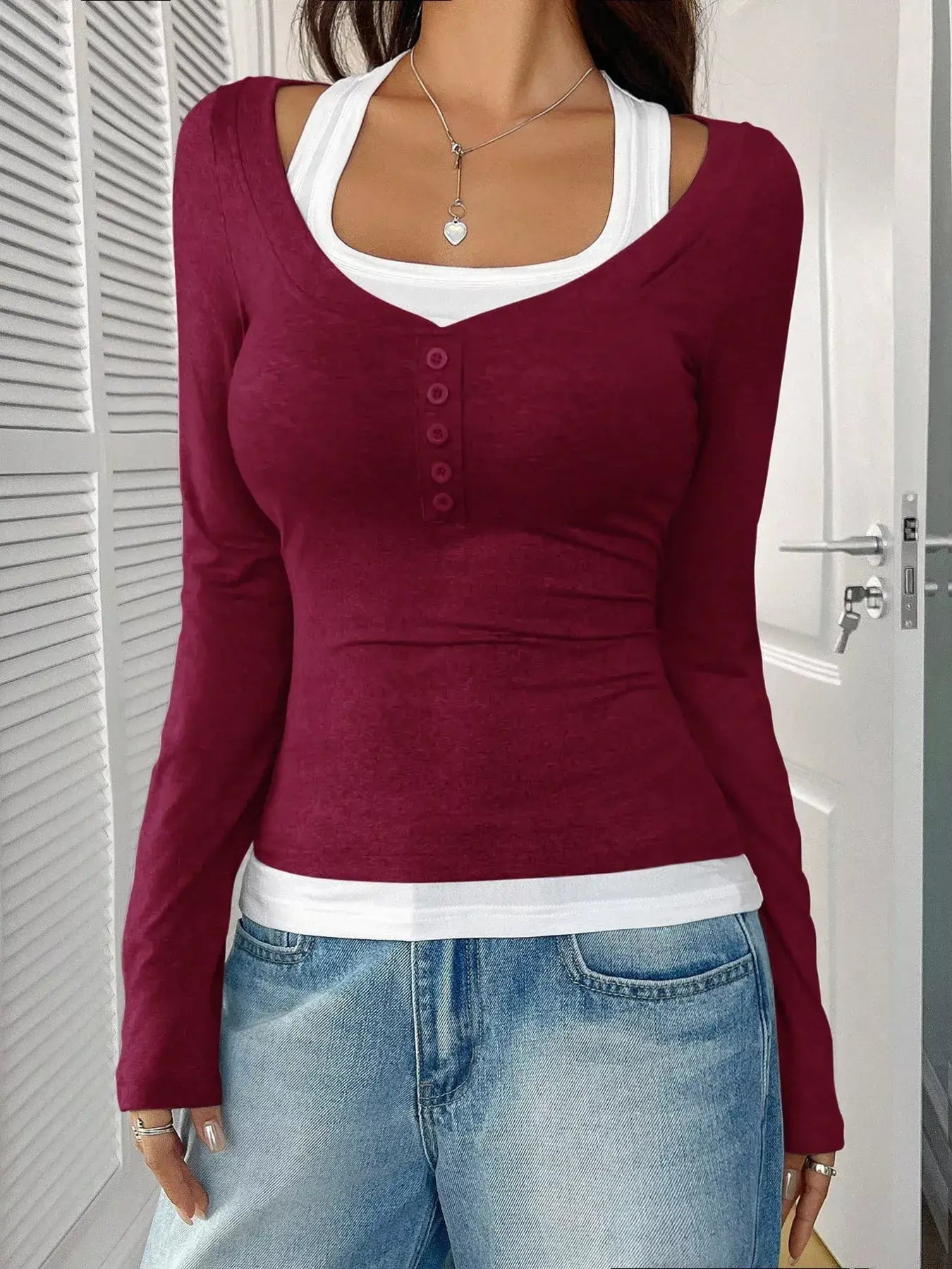 Chic scoop neck long sleeve t-shirt in burgundy layered over a white tank top, styled with casual jeans.