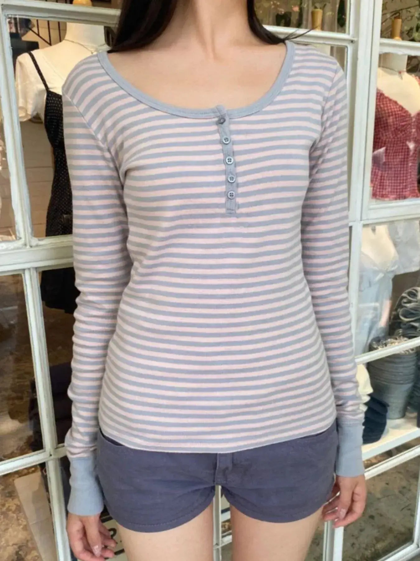 Model wearing a striped long sleeve henley t-shirt with buttoned front, styled with shorts.