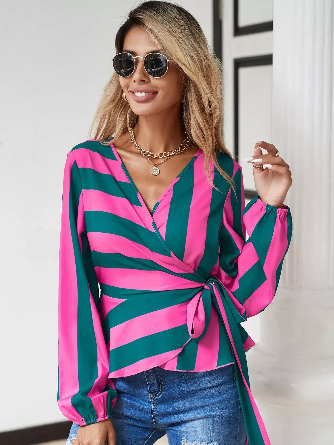 Striped wrap blouse with tie detail in pink and green stripes, featuring a flattering wrap design and long sleeves.