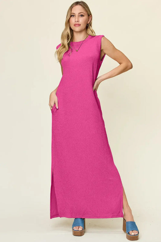 Model wearing a pink sleeveless maxi dress with a mock neck and side slit, showcasing a casual yet stylish look.