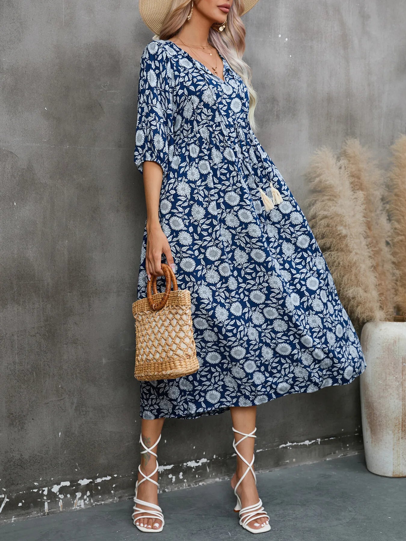 Model wearing Printed Tie Neck Midi Dress in navy floral print with a woven handbag and sandals.