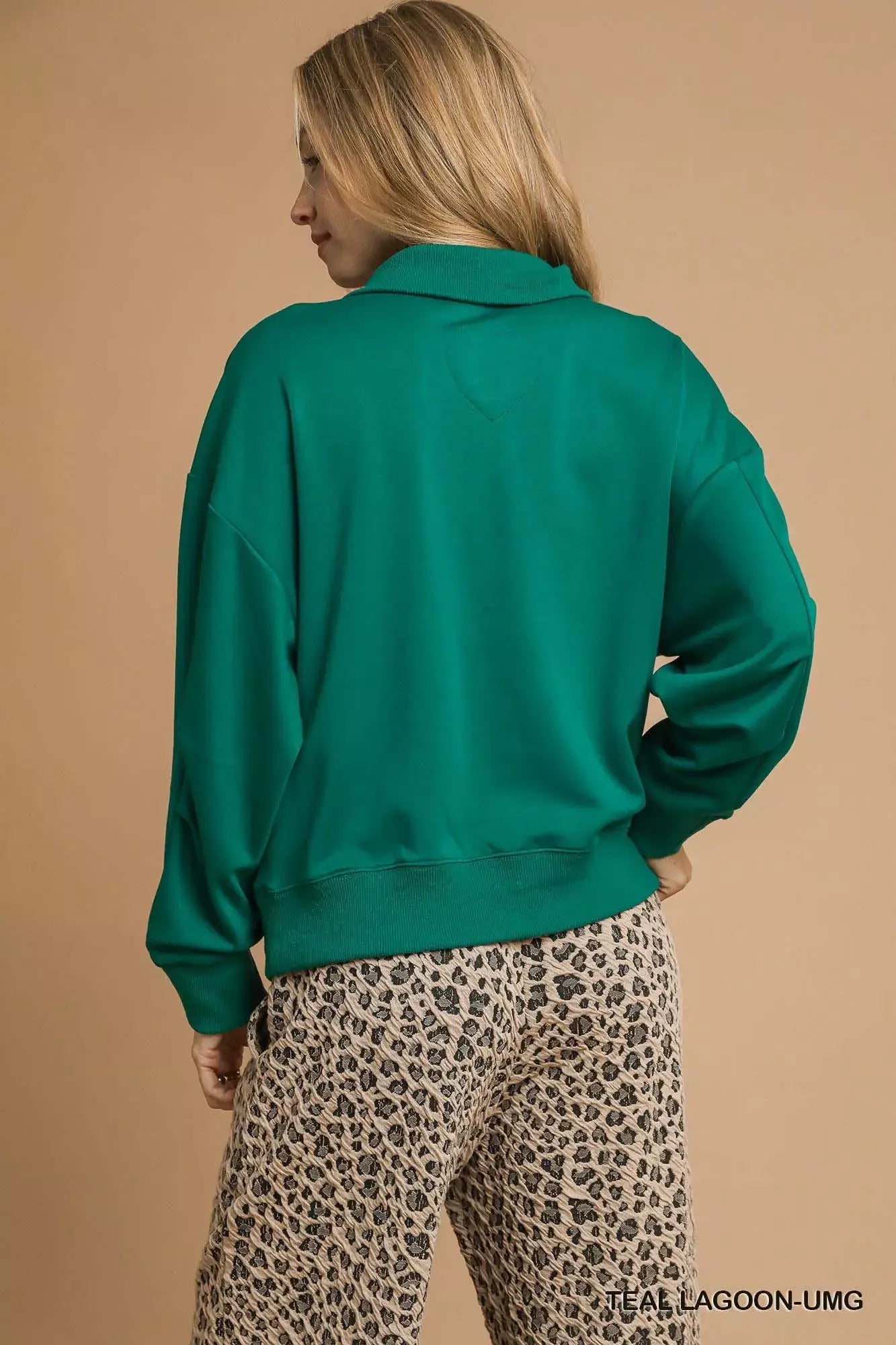 Back view of the Umgee Half Zip Drop Shoulder Sweatshirt in green, styled with leopard print pants.