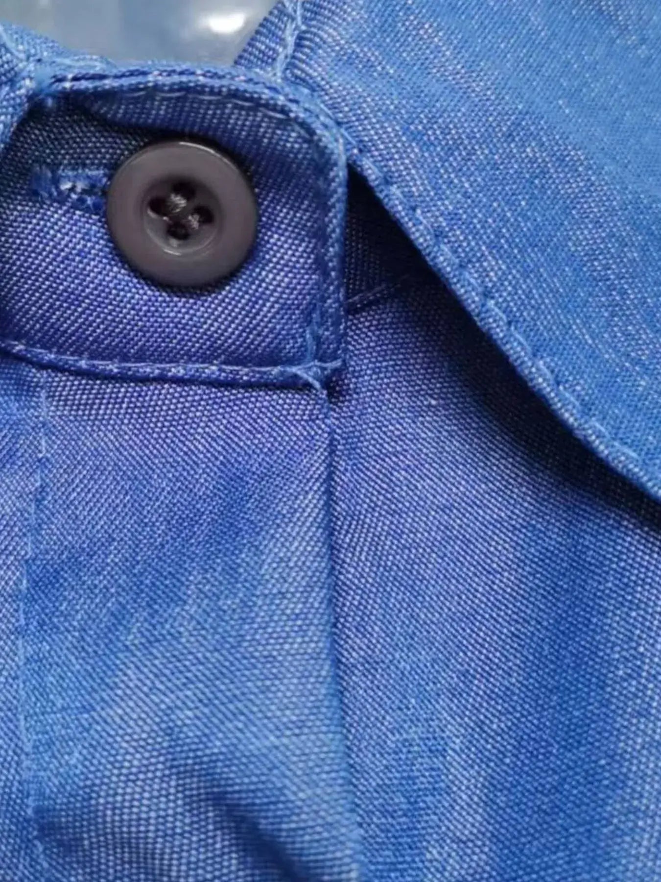 Close-up of button detail on a blue denim dress highlighting its quality fabric and stitching.