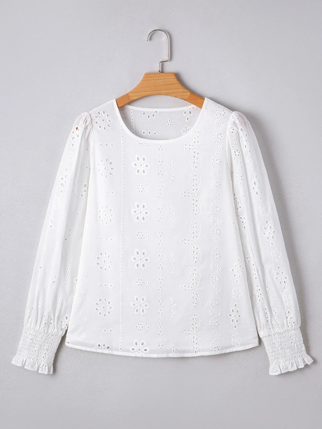 Eyelet Long Sleeve Blouse with Elastic Cuffs for Women on a hanger, featuring floral eyelet design and elastic cuffs.