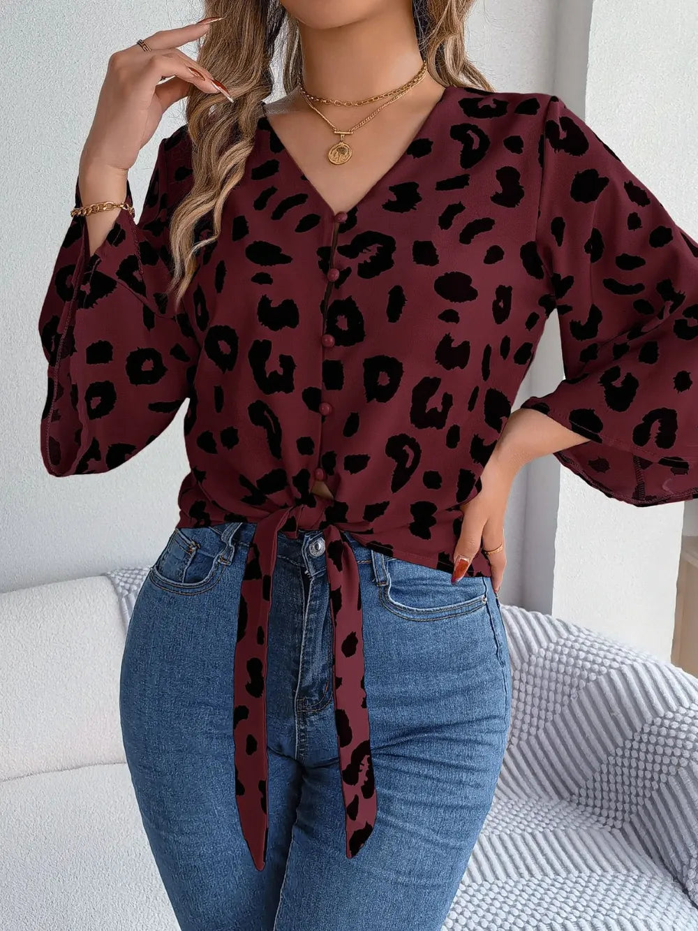Tied Button Up Leopard V-Neck Blouse worn with high-waisted jeans, featuring a tied front detail and stylish leopard print.