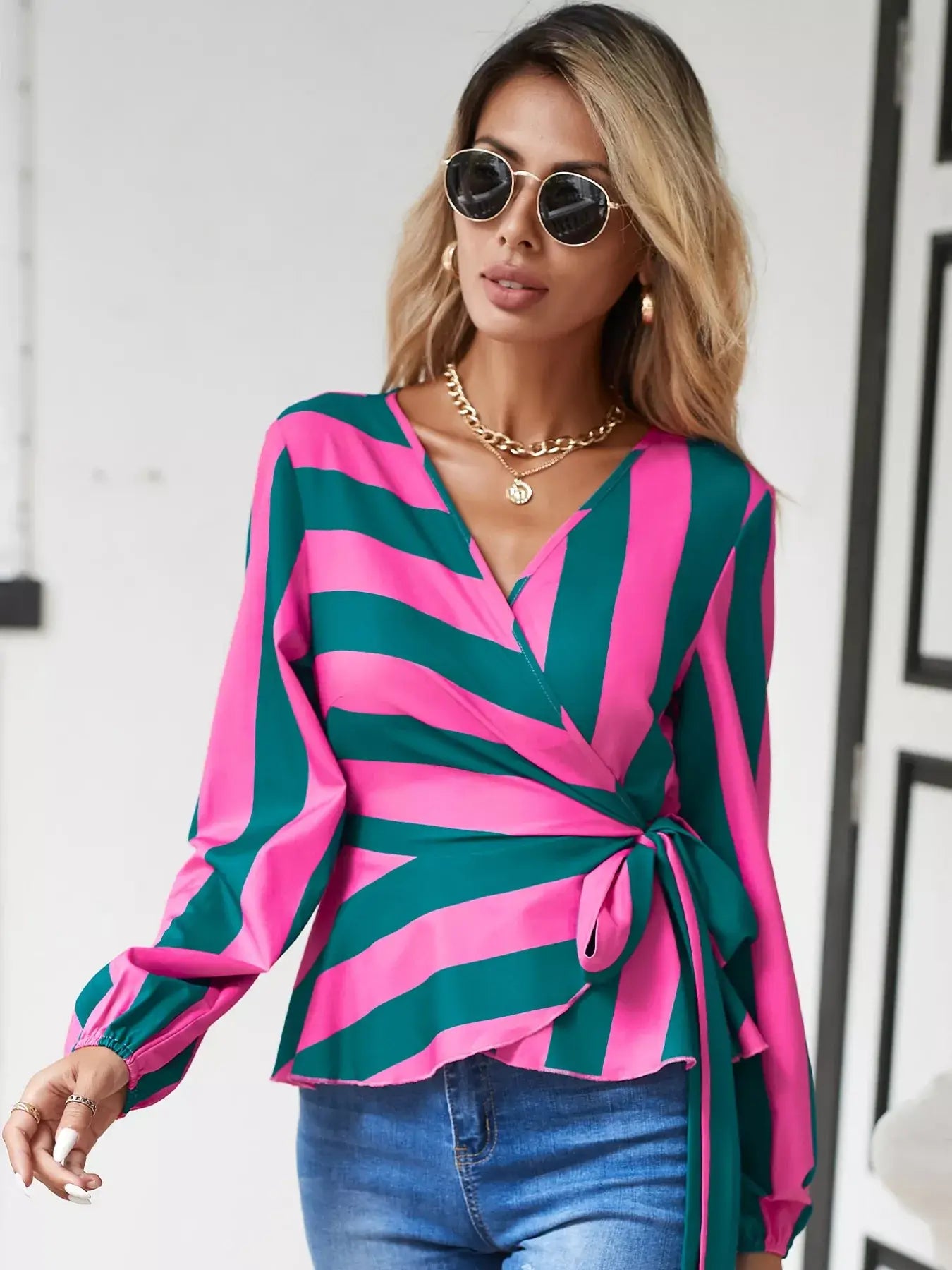 Striped wrap blouse with tie detail in pink and green, featuring a flattering wrap design and long sleeves.