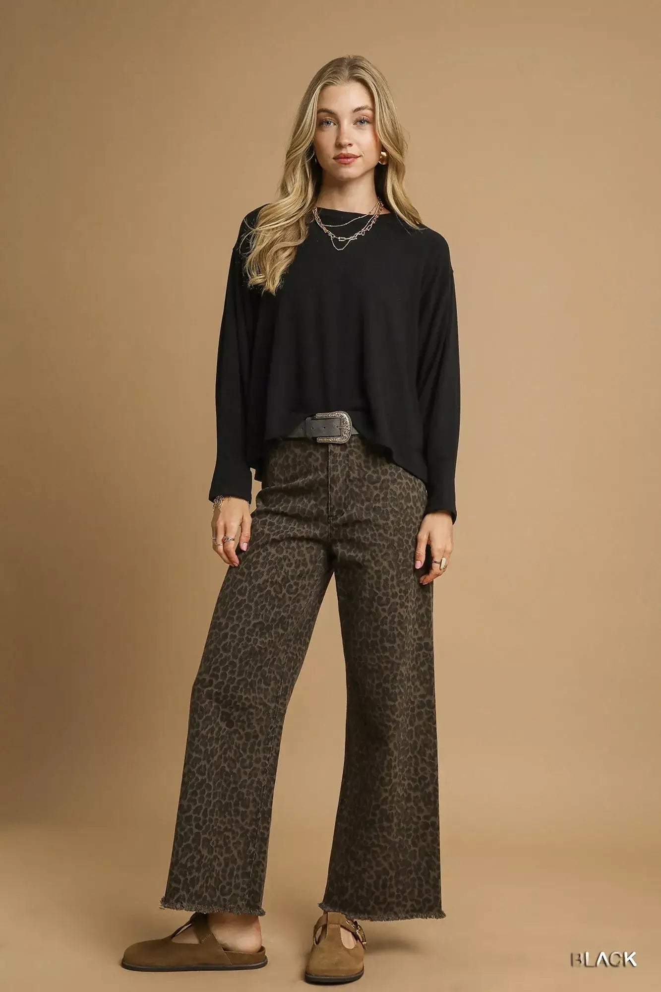 Model wearing a black oversized top with wide-leg leopard print pants against a neutral background.