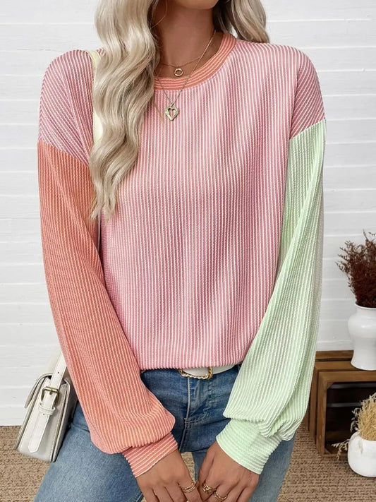 Woman wearing a Color Block Ribbed Long Sleeve T-Shirt in pink and green, styled with jeans and accessories.