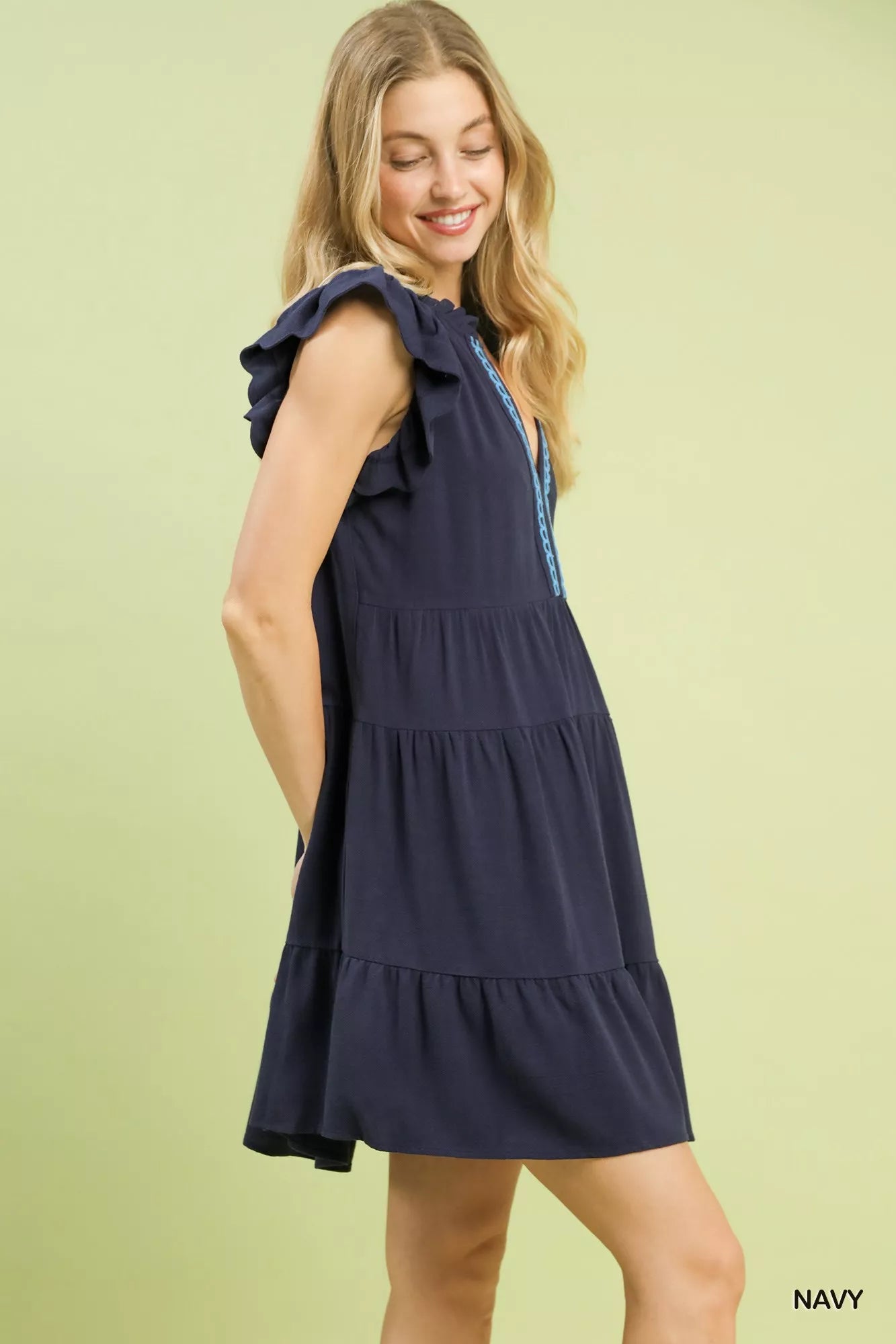 Model wearing Umgee Linen Tiered Baby Doll Dress in navy, showcasing its flutter sleeves and tiered design.