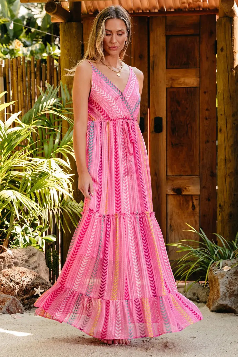 Printed Surplice Maxi Cami Dress on a model surrounded by greenery, showcasing a vibrant pink patterned design.