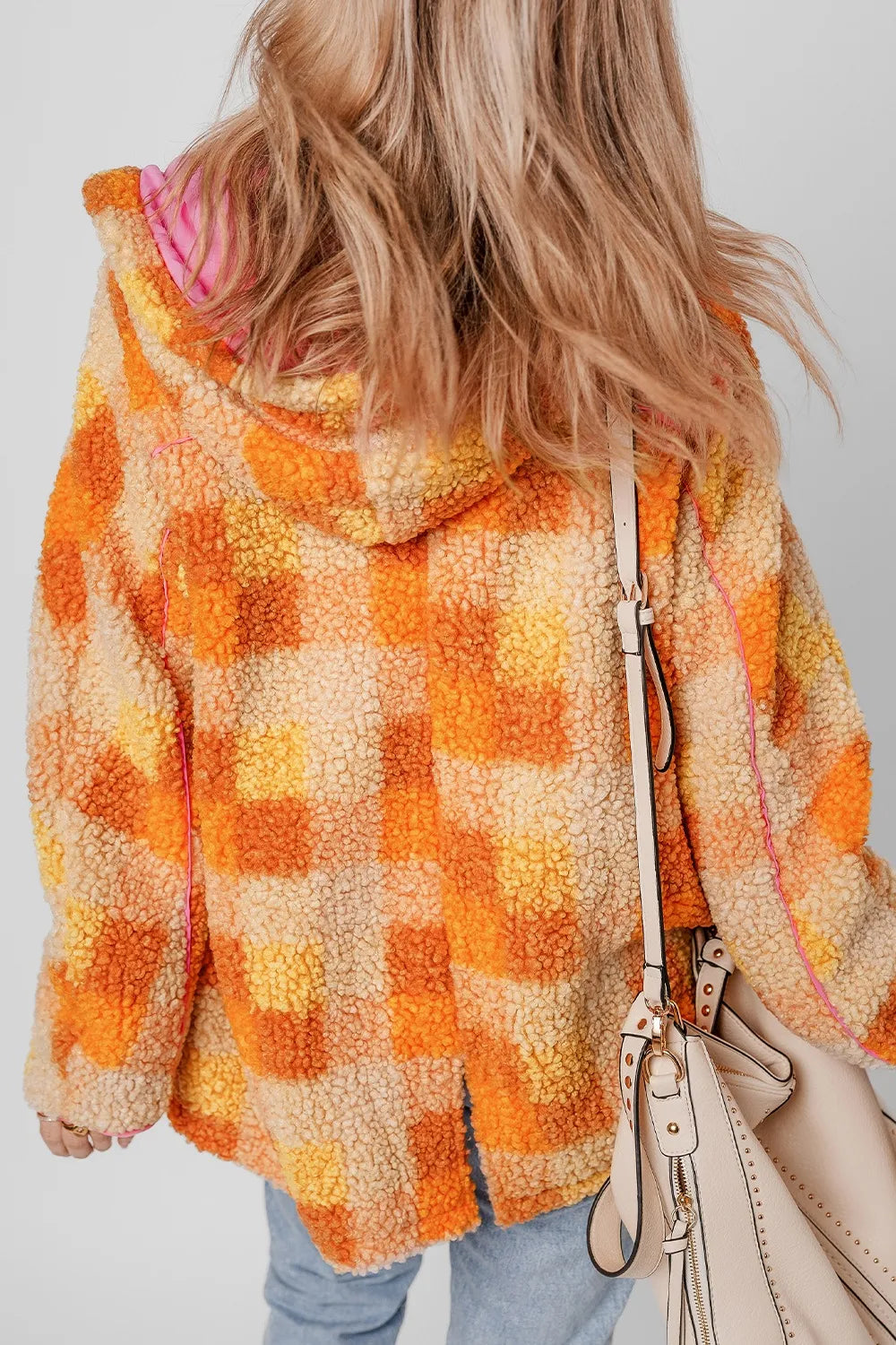 Back view of a model wearing a Checkered Long Sleeve Sherpa Hooded Jacket with multicolored checks and a stylish handbag.
