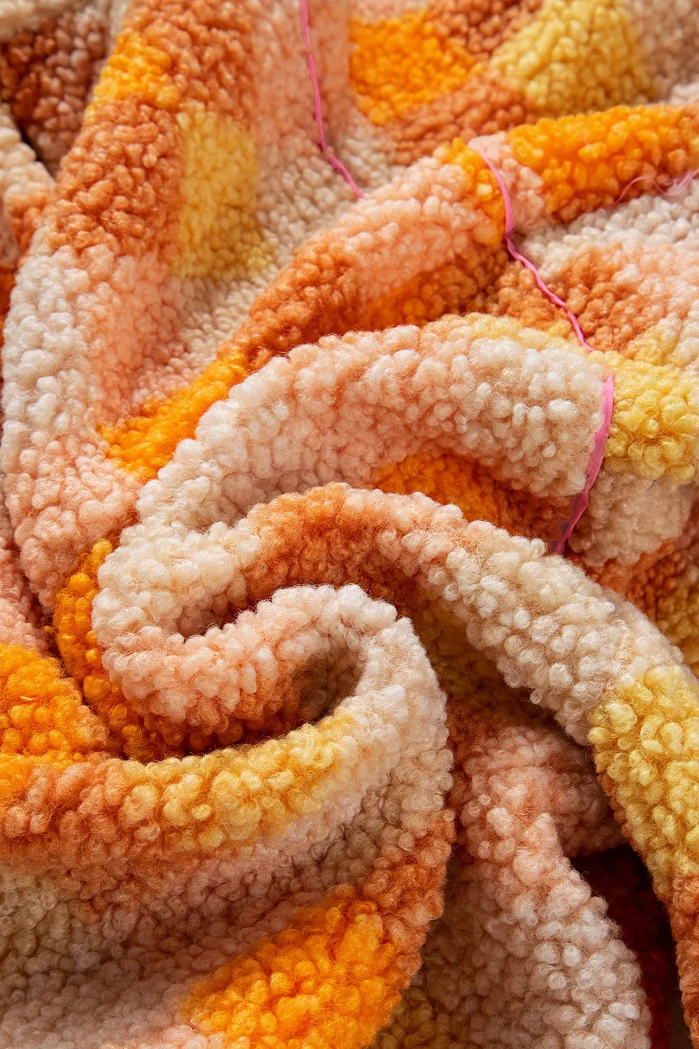 Checkered Long Sleeve Sherpa Hooded Jacket fabric close-up showing soft and cozy sherpa texture in warm orange and pink hues.
