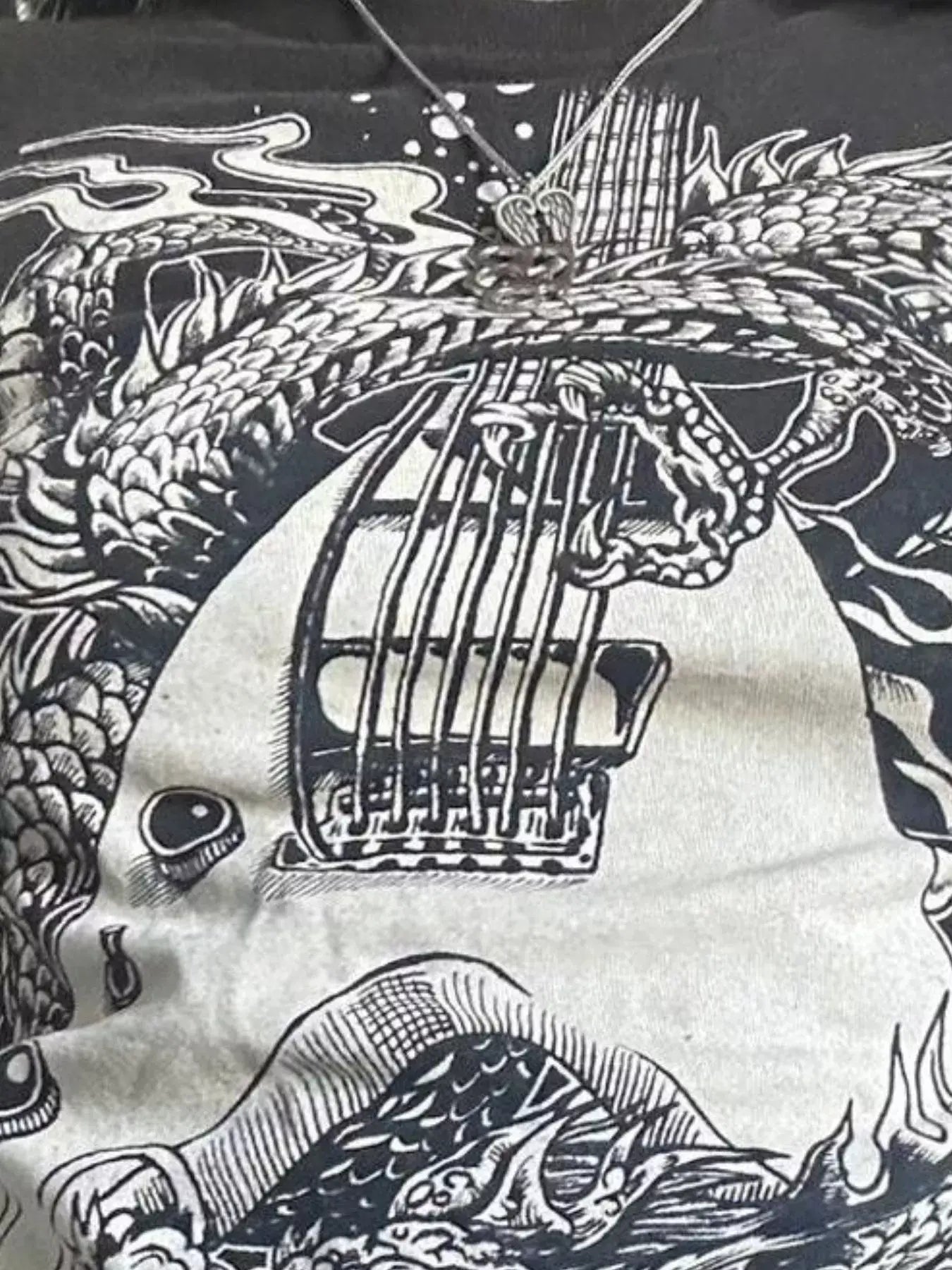 Graphic t-shirt featuring a detailed design of a guitar intertwined with dragon imagery.