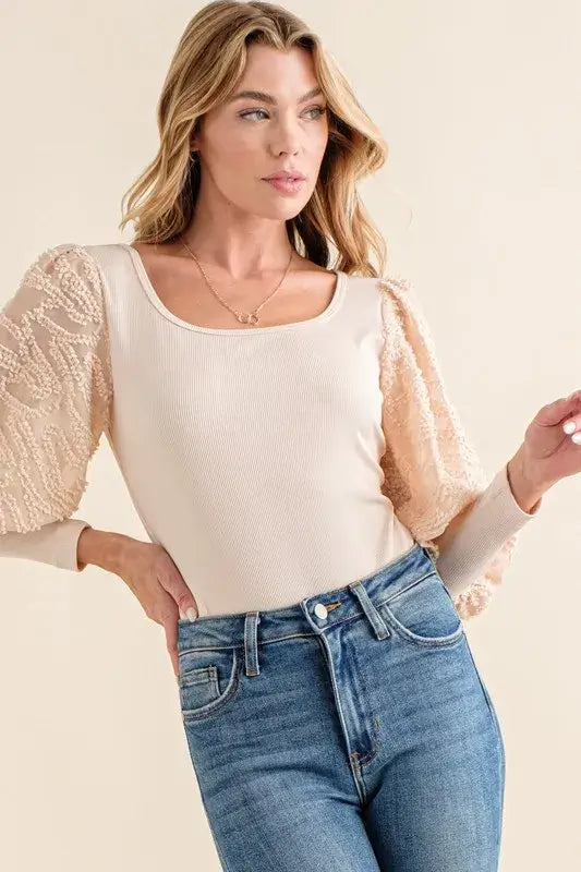 Textured puff sleeve bodysuit featuring elegant lace detail and puff sleeves, styled with high-waisted jeans.