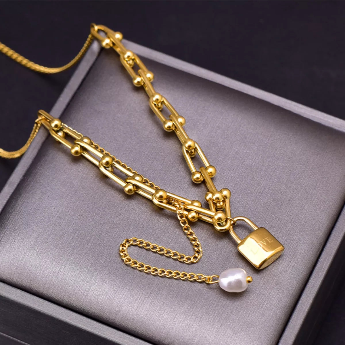 18K Gold-Plated Lock Pendant Necklace displayed on a gray box, featuring synthetic pearl and titanium steel accents.