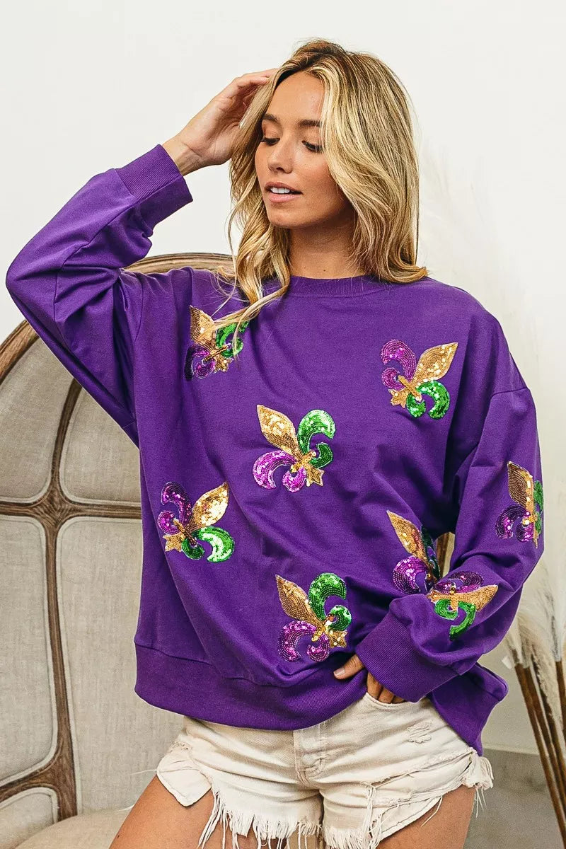 Model wearing BiBi Fleur De Lis Sequin Patches Mardi Gras Sweatshirt in purple with sequin details.