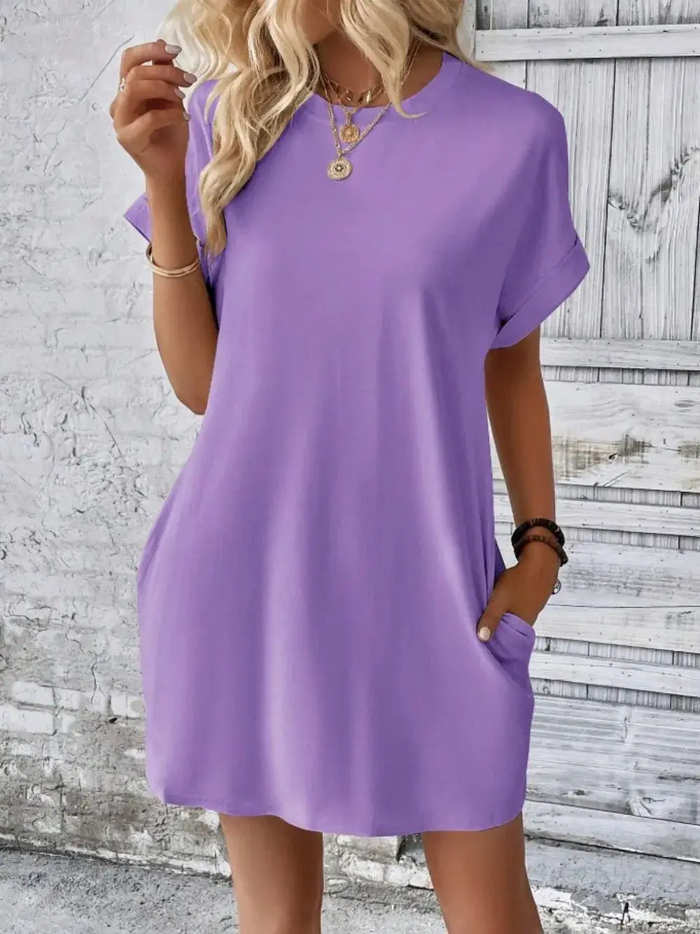 Model wearing a pocketed round neck short sleeve dress in lavender with a relaxed fit, styled with accessories.