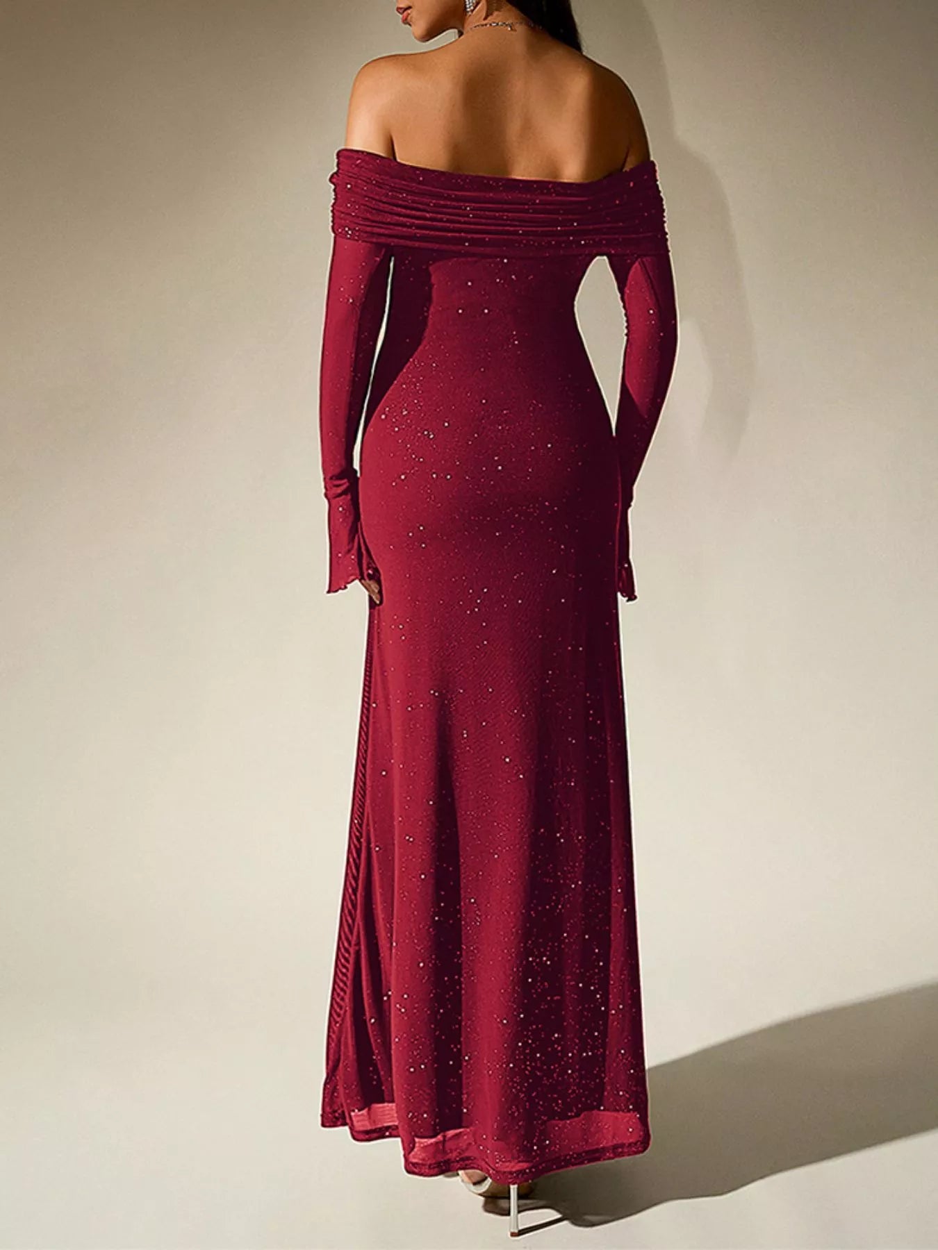 Back view of a woman wearing a Glitter Off-Shoulder Maxi Dress in burgundy, adorned with sparkling glitter details.